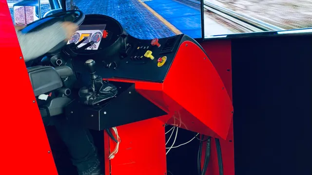 Conductor en la cabina roja del simulador, con las manos en el volante