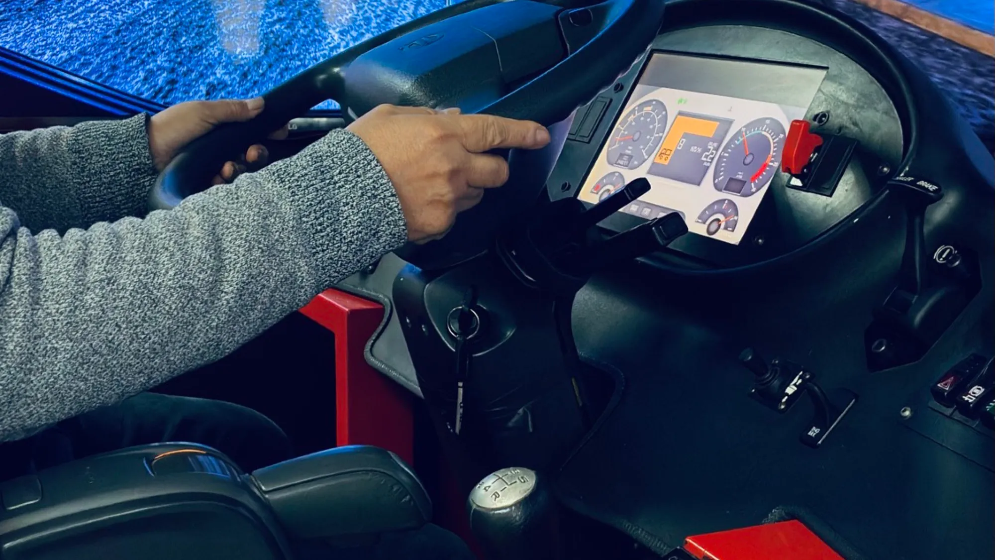 Manos de un conductor en el volante del simulador, junto al tablero de instrumentos
